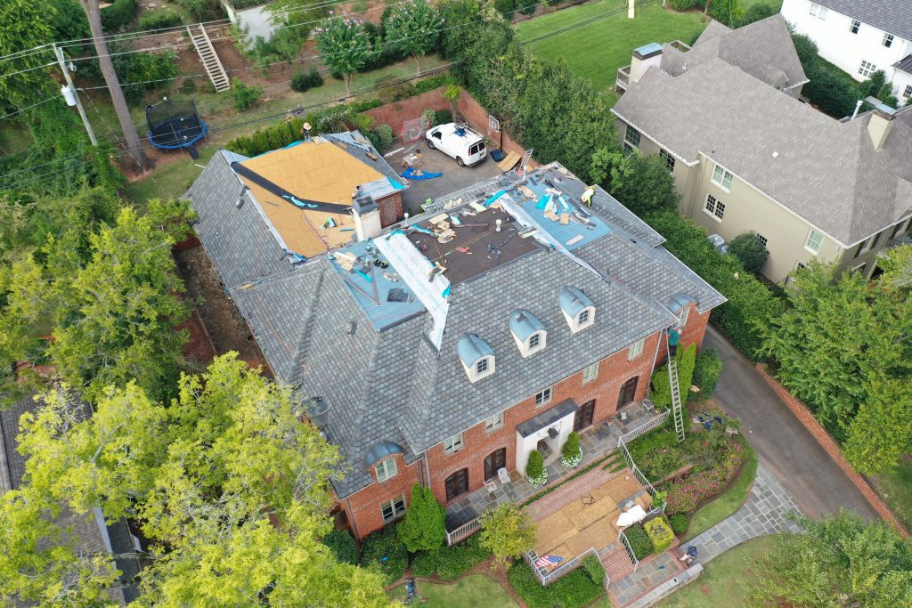 Overhead shot of a large brick house in the middle of a roof install.